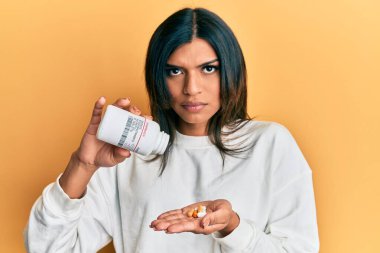 Genç Latin transseksüel kadın elinde haplar tutuyor şüpheci ve gergin, sorun yüzünden somurtuyor. negatif kişi. 