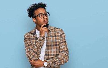 Sakallı, sıradan giyinmiş, çenesi üzerinde gözlüklü soru soran, düşünceli, genç Afro-Amerikan adam. Düşünceli bir yüzle gülümsüyor. şüphe kavramı. 