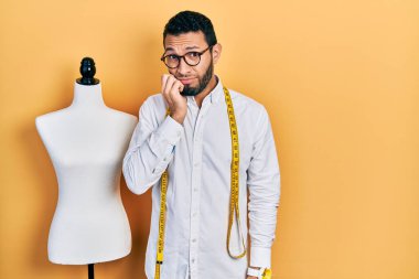 Sakal terzisi olan İspanyol bir adam manikinin yanında duruyor. Ağzı tırnak yerken gergin ve stresli görünüyor. anksiyete. 