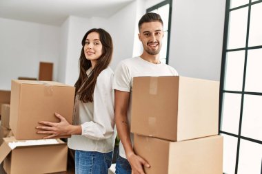 Genç İspanyol çift mutlu bir şekilde gülümsüyor. Karton kutular yeni evlerinde taşınıyor..