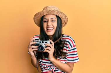 Yaz şapkası takan genç İspanyol kadın elinde antika kamerayla gülüyor ve kahkahalarla gülüyor.. 