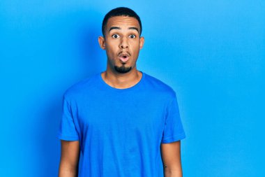 Genç Afro-Amerikan adam günlük mavi tişört giyiyor. Şaşırtıcı bir ifade, korku ve heyecan dolu bir yüz ifadesi var.. 