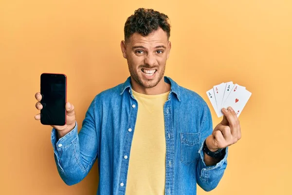 Homem Hispânico Jovem Segurando Cartões Poker Smartphone Mostrando Tela Branco — Fotografia de Stock