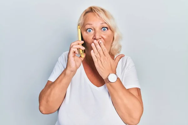 Mujer Rubia Mediana Edad Conversando Smartphone Cubriendo Boca Con Mano —  Fotos de Stock