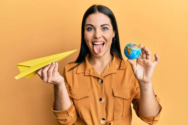 Jovem Morena Segurando Avião Papel Bola Mundo Furando Língua Feliz — Fotografia de Stock