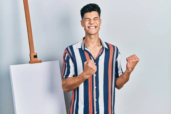 Young Hispanic Man Standing Close Empty Canvas Excited Success Arms — 스톡 사진