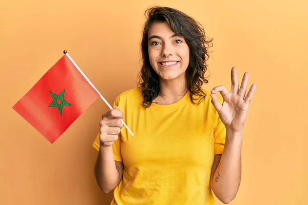 Jovem Hispânica Segurando Bandeira Morocco Fazendo Sinal Com Dedos Sorrindo — Fotografia de Stock