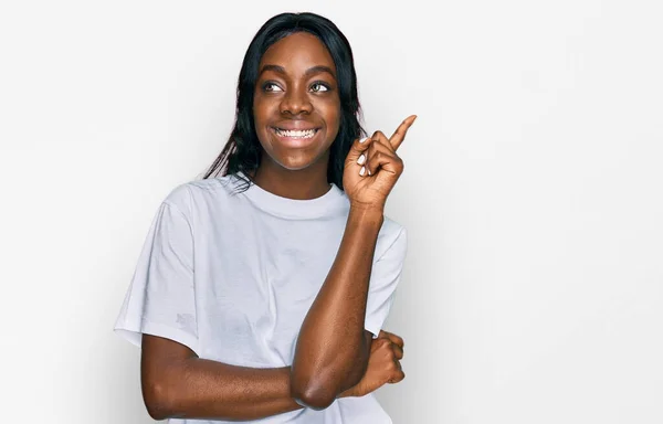カメラを見ている側に手と指で指して 顔に大きな笑顔でカジュアルな白いTシャツを着て若いアフリカ系アメリカ人女性 — ストック写真