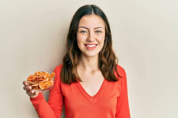 Jovem Morena Segurando Tigela Laranja Seca Olhando Positivo Feliz Sorrindo — Fotografia de Stock