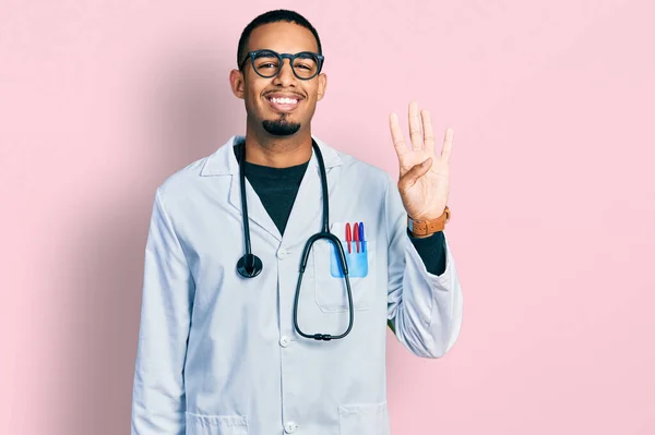 身穿医生制服和听诊器的年轻的非洲裔美国人 带着自信和快乐的微笑 用第四指尖示人 — 图库照片