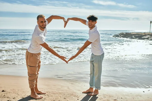 Genç Eşcinsel Çift Gülümseyerek Kumsalda Kollarıyla Kalp Sembolü Yapıyor — Stok fotoğraf