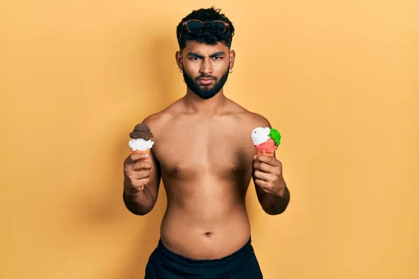 Arabský Muž Plnovousem Plavkách Pojídající Dvě Zmrzliny Skeptický Nervózní Mračí — Stock fotografie