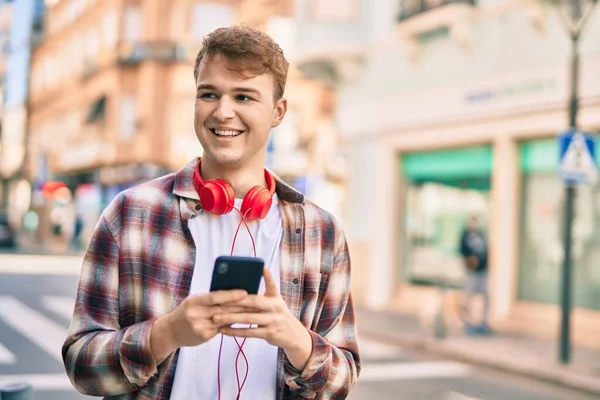 Νεαρός Καυκάσιος Άνδρας Χαμογελά Χαρούμενος Χρησιμοποιώντας Smartphone Στην Πόλη — Φωτογραφία Αρχείου