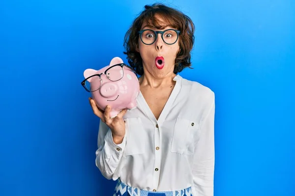 Young Brunette Woman Holding Piggy Bank Glasses Scared Amazed Open — Stock Photo, Image