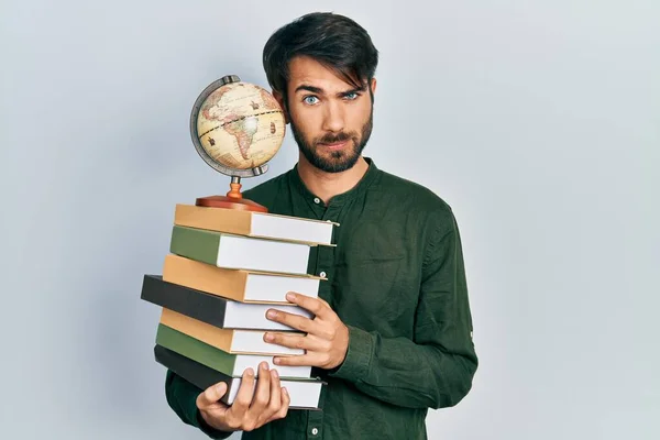 Joven Hombre Hispano Sosteniendo Libros Bola Del Mundo Escéptico Nervioso — Foto de Stock