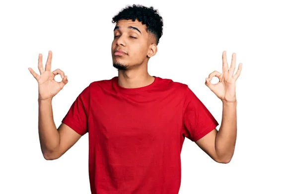 身穿休闲红T恤的年轻的非洲裔美国人放松 闭上双眼微笑 用手指做冥想动作 瑜伽概念 — 图库照片