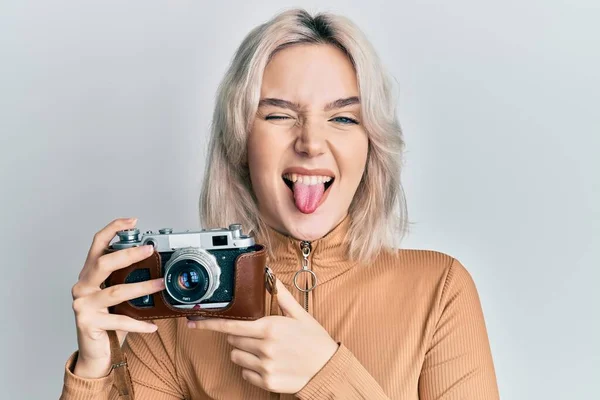 Menina Loira Jovem Segurando Câmera Vintage Furando Língua Feliz Com — Fotografia de Stock