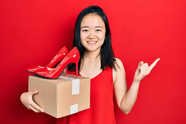 Young Chinese Girl Holding Red High Heel Shoes Package Smiling — 图库照片