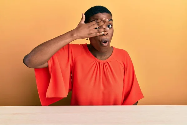 Jovem Afro Americana Vestindo Roupas Casuais Sentada Mesa Espreitando Choque — Fotografia de Stock