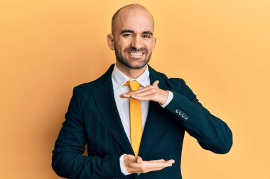 İş elbisesi giyen ve kravatlı genç bir adam. Büyük ve büyük boy işareti gösteren elleri var. Ölçüm sembolü. Kameraya bakıp gülümsüyor. ölçüm kavramı. 