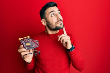 Küçük bir süpermarket arabası taşıyan İspanyol bir genç. Ciddi bir yüz ifadesi var. Çene ve çeneyle ilgili sorular soruyor. 