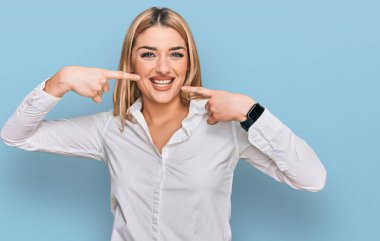 Günlük kıyafetler giyen, neşeli gülümseyen, parmaklarıyla ve ağzıyla işaret eden beyaz bir kadın. diş sağlığı kavramı. 
