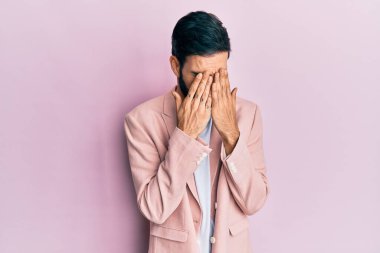 Ağlarken yüzünü ellerle kapatan üzgün bir ifadeyle iş ceketi giyen İspanyol genç bir adam. depresyon kavramı. 