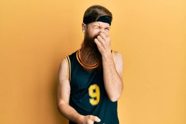 Uzun sakallı, basketbol forması giyen, pis ve iğrenç bir koku alan, nefesini burnunda tutan kızıl saçlı bir adam. Kötü kokuyor. 