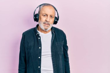 Sakallı yakışıklı, müzik dinleyen, kulaklık takan, ciddi bir ifadeyle rahatlamış yaşlı bir adam. Basit ve doğal bir şekilde kameraya bakıyorsun.. 