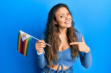 Zimbabwe bayrağı tutan genç İspanyol kız gülümsüyor. 