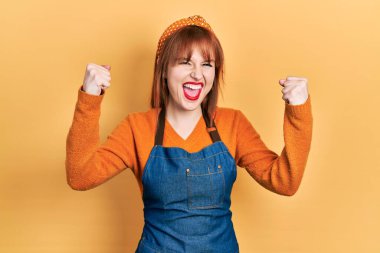 Kızıl saçlı genç kadın gururla bağırıyor zaferi ve başarıyı kutluyor. Kollarını kaldırıp heyecanla bekliyor. 