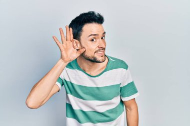 Gündelik kıyafetler giyen, ağzı kulaklarında gülümseyen genç İspanyol bir adam dedikoduları ve dedikoduları dinliyor. Sağırlık kavramı. 