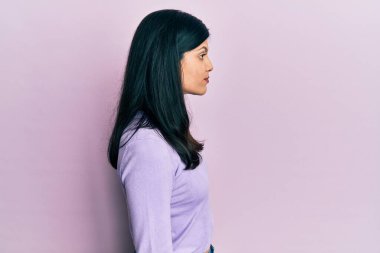 Latin kökenli genç bir kadın günlük giysiler giyiyor. Tarafını arıyor, profil pozu veriyor. Doğal bir yüzü ve kendine güvenen bir gülümsemesi var.. 