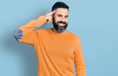 Hispanic man with beard wearing casual winter sweater smiling pointing to head with one finger, great idea or thought, good memory 