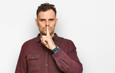 Gündelik kıyafetler giyen genç İspanyol adam parmakları dudaklarında sessiz olmak istiyor. sessizlik ve gizli konsept. 