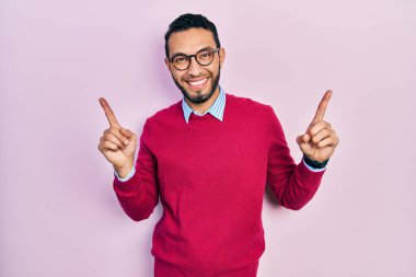 Hispanic man with beard wearing business shirt and glasses smiling confident pointing with fingers to different directions. copy space for advertisement 