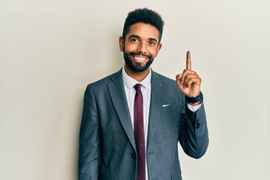 Yakışıklı, sakallı, takım elbiseli ve kravatlı bir numaralı parmağıyla kendini beğenmiş ve mutlu gülümseyen adam.. 