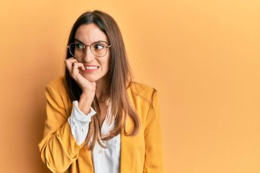 İş stili takan, gözlüklü, stresli ve gergin görünen elleri ağızdan tırnak yiyen genç ve güzel bir kadın. anksiyete. 