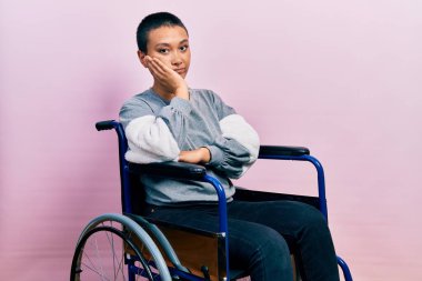 Tekerlekli sandalyede oturan güzel İspanyol kadın kollarını kavuşturup depresyondan sıkılmış ve yorgun görünüyor.. 