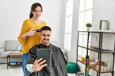 Kuaför kadın güzellik merkezinde saç keserken genç İspanyol adam perdeye bakıyor..