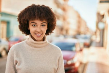 Genç İspanyol kız gülümseyerek şehirde mutlu mesut dikiliyor..