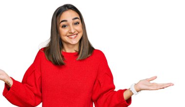 Güzel esmer kadın, günlük kışlık süveter giyer, gülümser, avuçlarını açar, sunar, reklamını yapar, karşılaştırır ve dengede durur. 