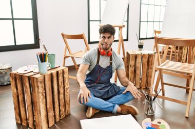 Sanat stüdyosunda oturan genç İspanyol adam dudaklarıyla balık suratı yapıyor, çılgınca ve komik bir jest. Komik ifade. 