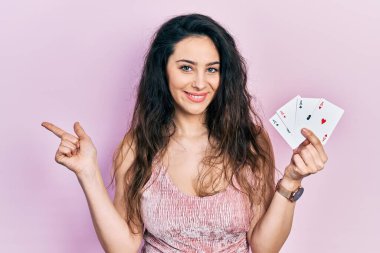 Poker kartları tutan genç İspanyol kadın mutlu bir şekilde elini ve parmağını yana doğru gösteriyor. 