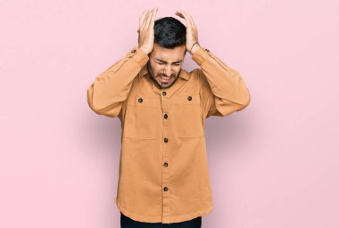 İspanyol asıllı genç adam gündelik giysiler giyiyor. Baş ağrısı çekiyor. Acı ve migren yüzünden çaresiz ve stresli. Eller başının üstünde.. 