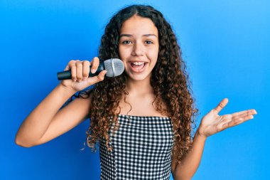 Genç İspanyol kız mikrofon kullanarak şarkı söylüyor başarıyı mutlu bir gülümsemeyle kutluyor ve kazanan el kaldırarak ifade ediyor. 