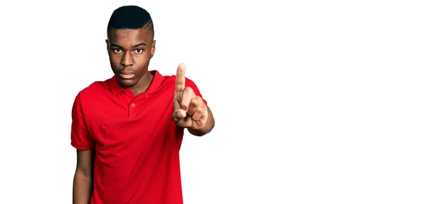 若いアフリカ系アメリカ人の男を着てカジュアルな赤いTシャツを指差して指を上げて怒りの表情 ジェスチャーを示さない — ストック写真