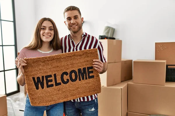 Joven Pareja Caucásica Sonriendo Feliz Celebración Bienvenida Felpudo Nuevo Hogar —  Fotos de Stock