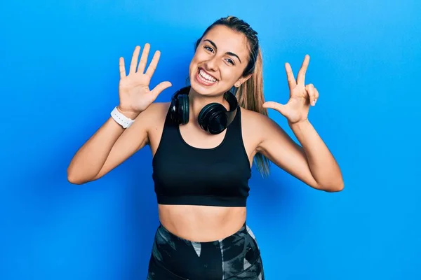 Beautiful Hispanic Woman Wearing Gym Clothes Using Headphones Showing Pointing — 스톡 사진