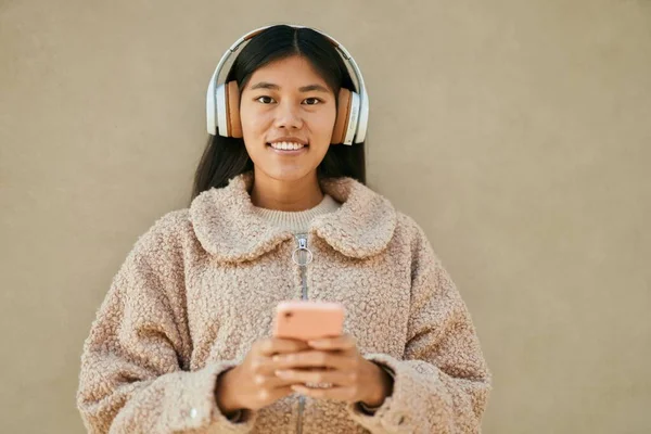 Young asian woman smiling happy using smartphone and headphones at the city.